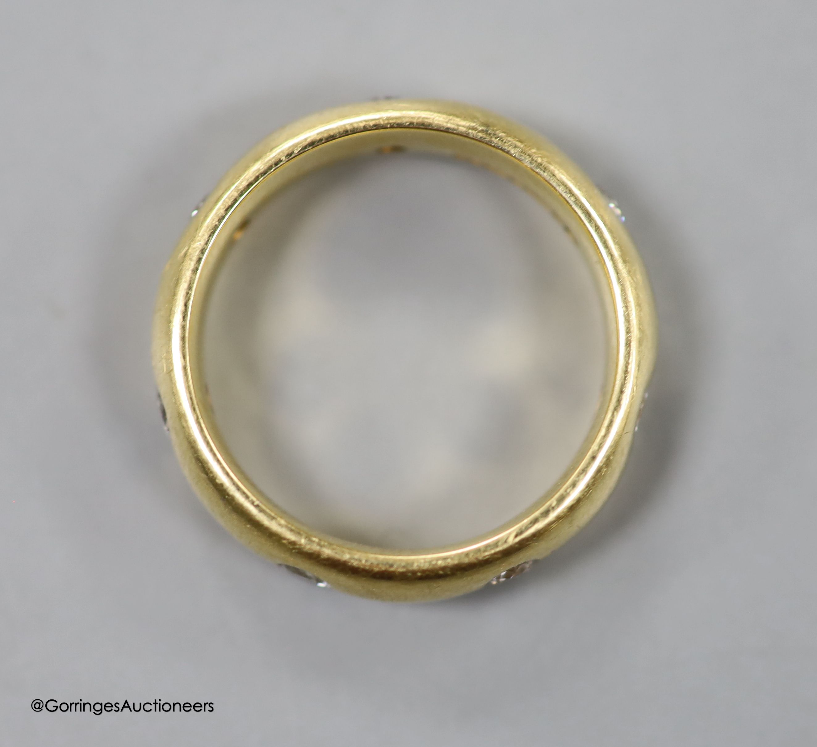 A modern 18ct gold and seven stone diamond gypsy set band, size M, gross 7.6 grams.